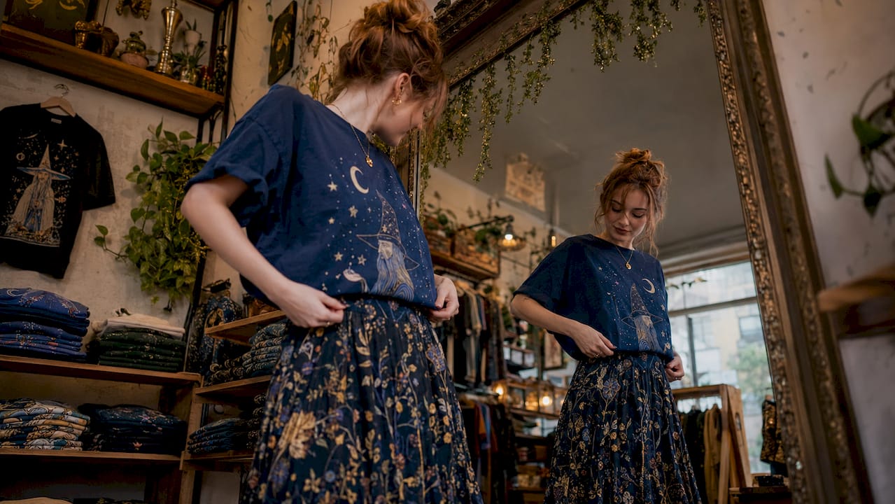 Woman styling graphic tee in loft mirror