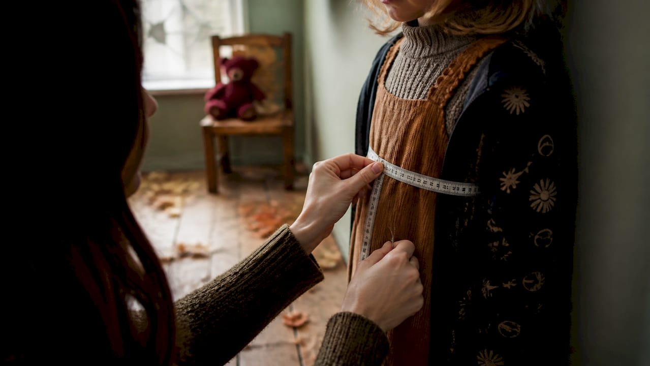 Parent measuring child's chest with tape