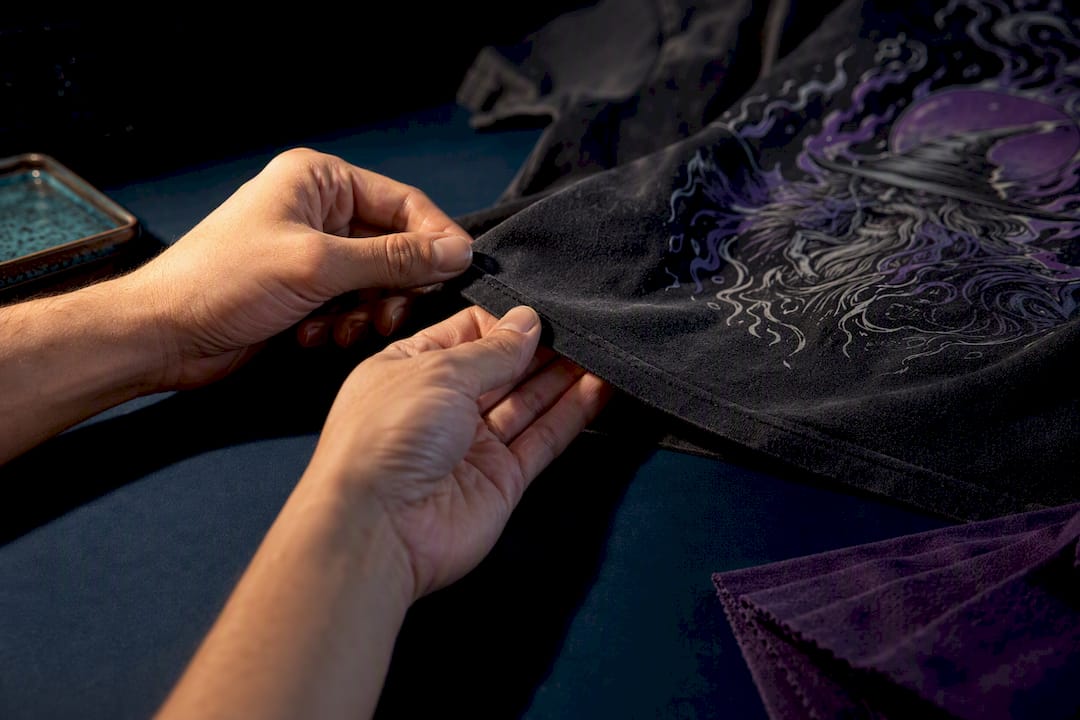 Hands inspecting tee fabric and print